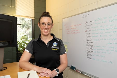 Employee Kristina Stulken posing at desk in front of white board